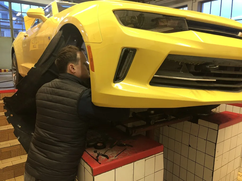 Praca przy żółtym Chevrolecie Camaro w warsztacie
